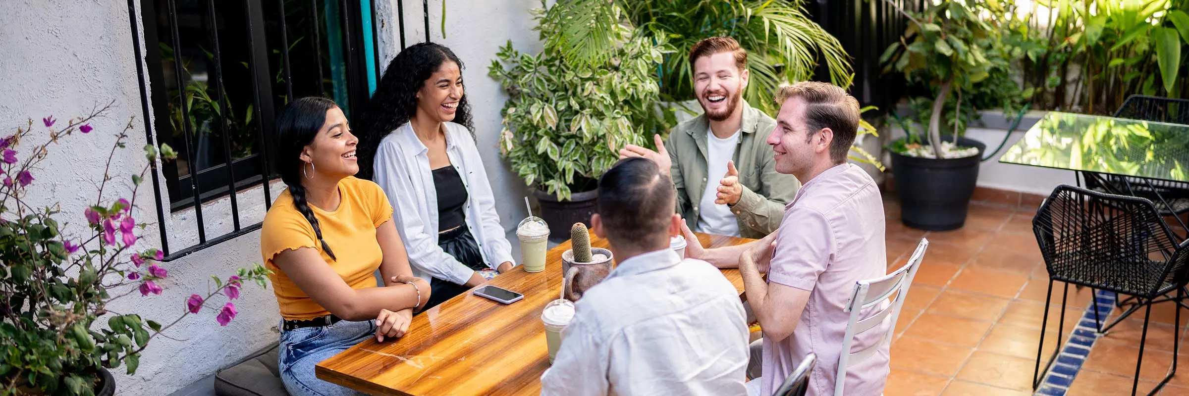 Image of friends gathered around a table in a courtyard