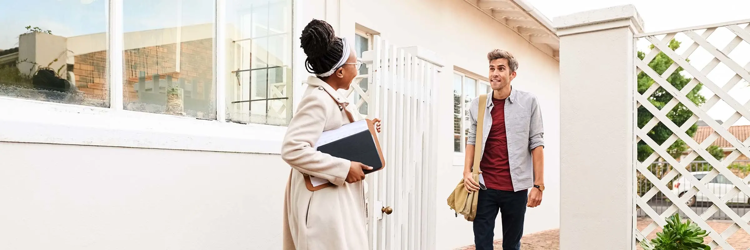 Real estate agent greeting a client before walking inside to tour a house.