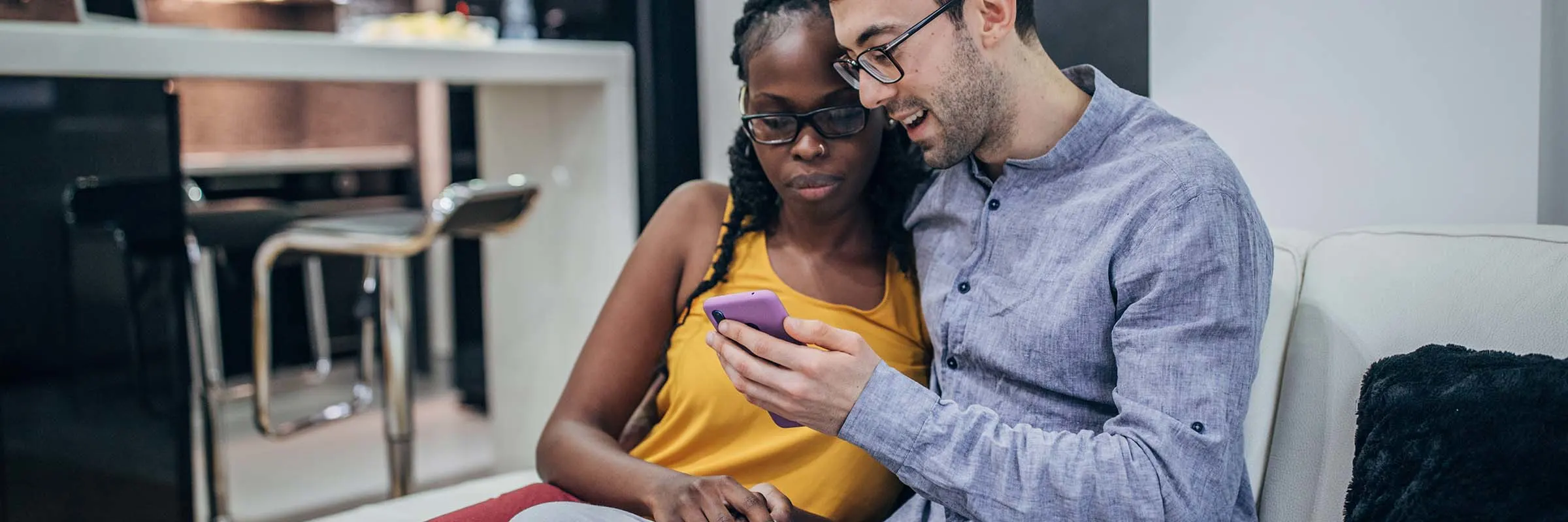 Couple looking at a phone while sitting on their sofa