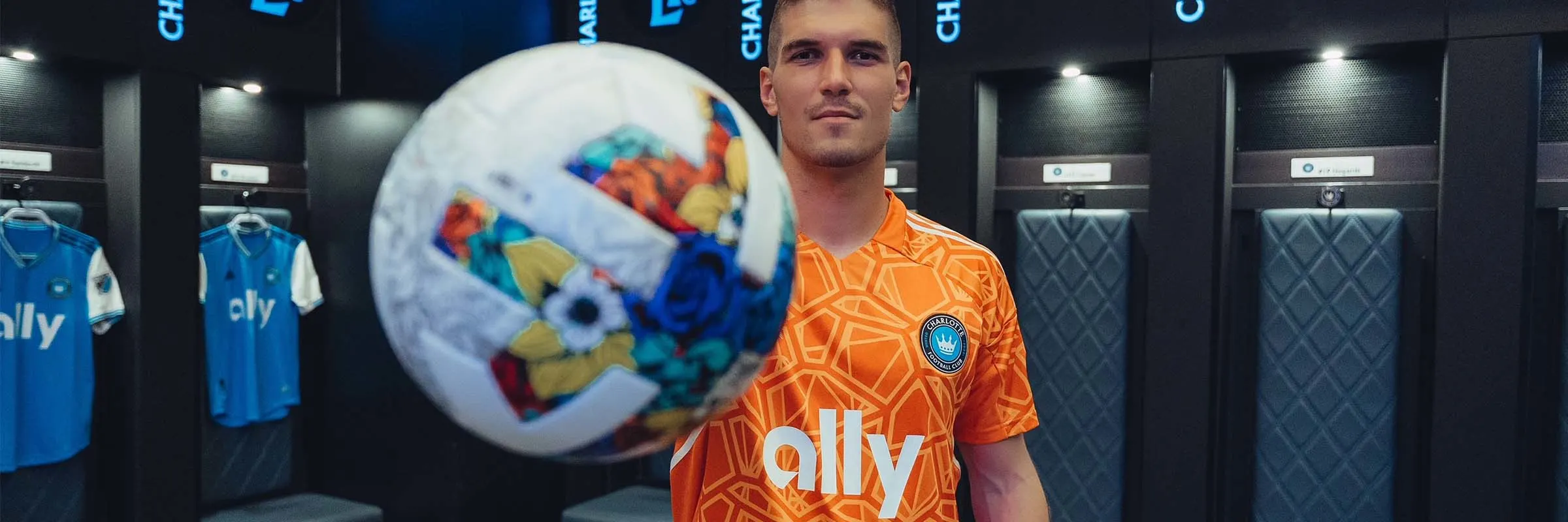 Kristijan Kahlina stands in the Charlotte FC locker room holding a soccer ball in front of the camera