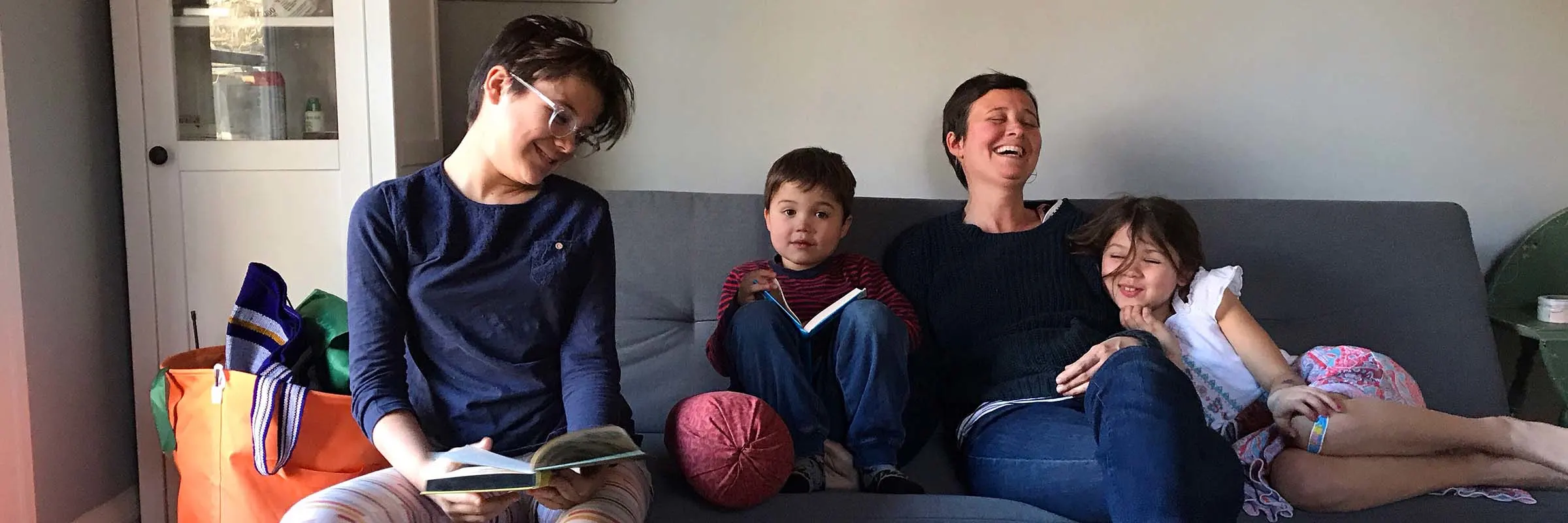  A mother laughs while sitting on a couch with her three children.