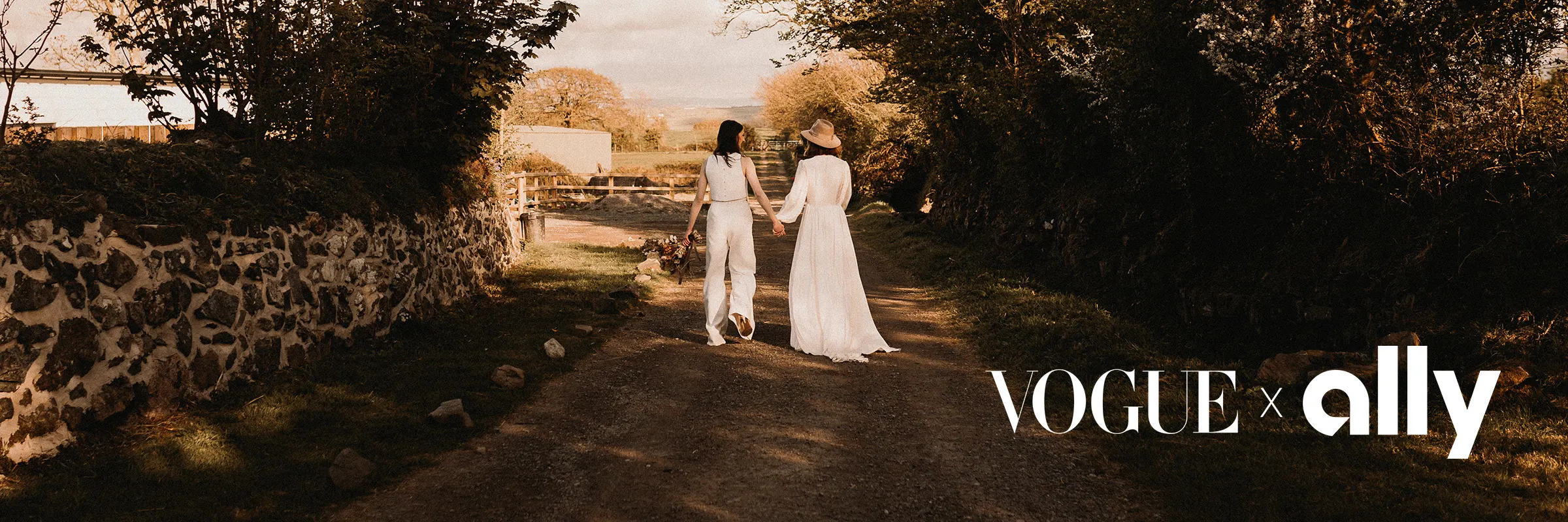 Young couple in wedding clothes walks down a dirt countryside road
