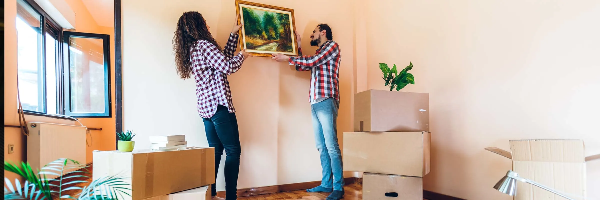 Man and woman hang picture as unpacking in new home