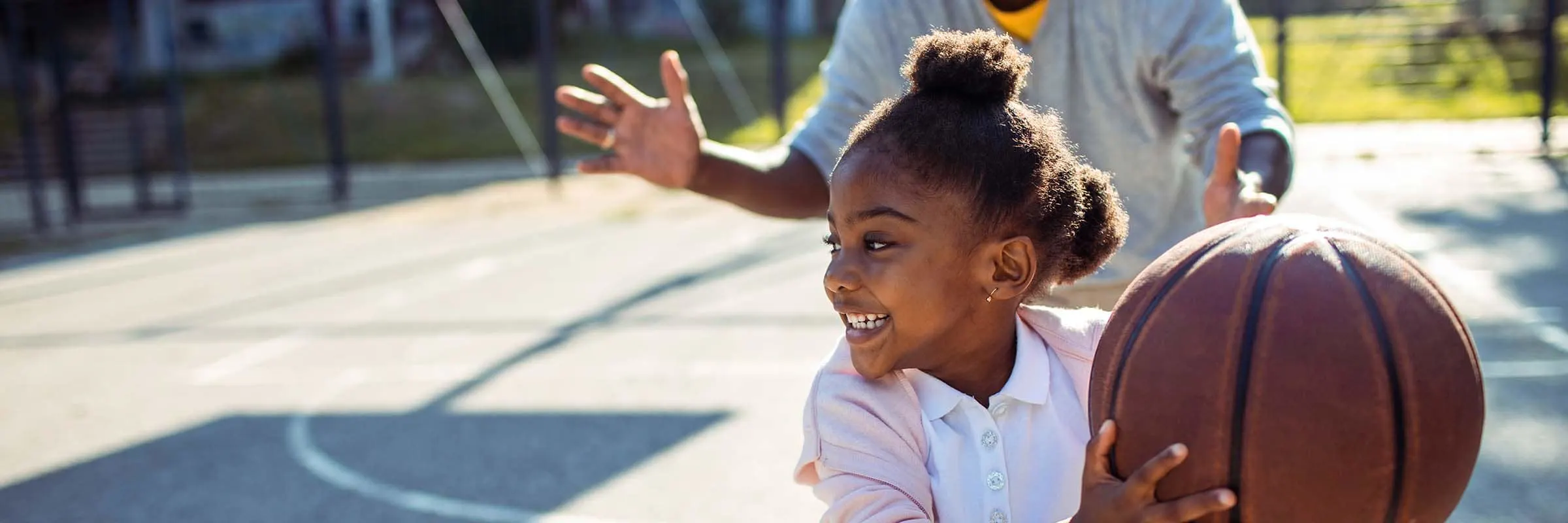 Close up of a father taking his daughter to play some basketball in the park