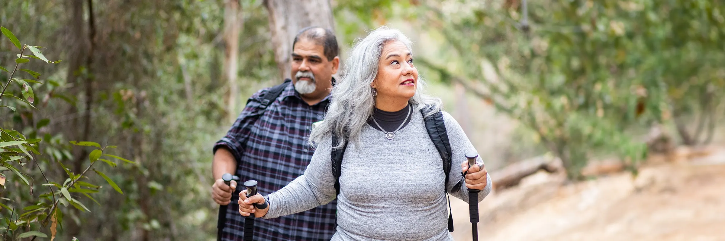 Older couple hiking together through the woods.