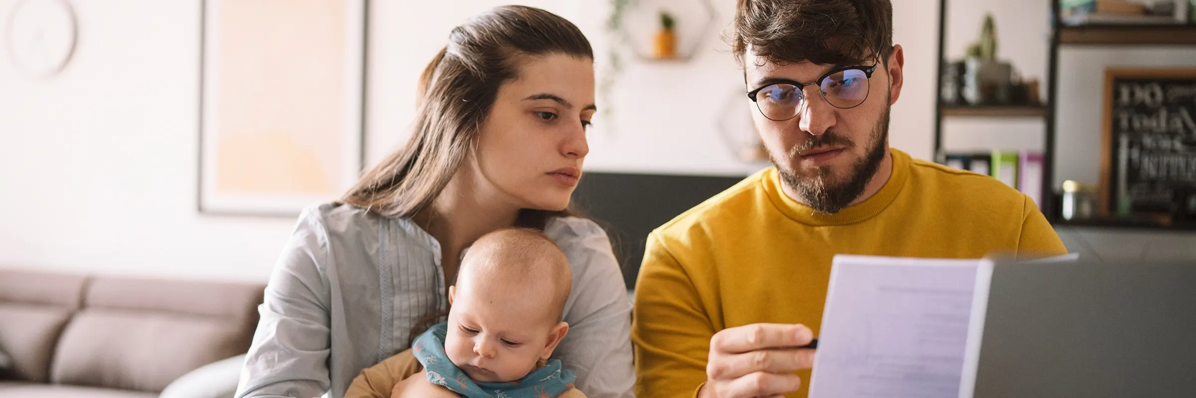 A couple with a baby look over financial statements together at a table