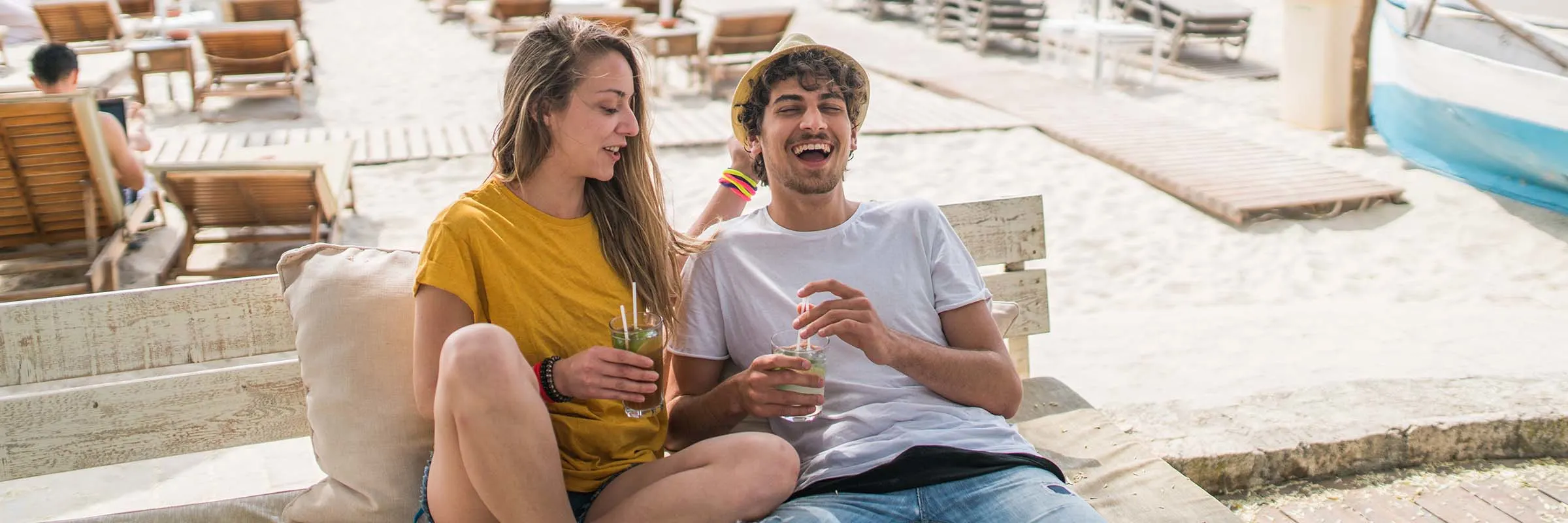 Young couple drinking cocktails on the beach in the cafe