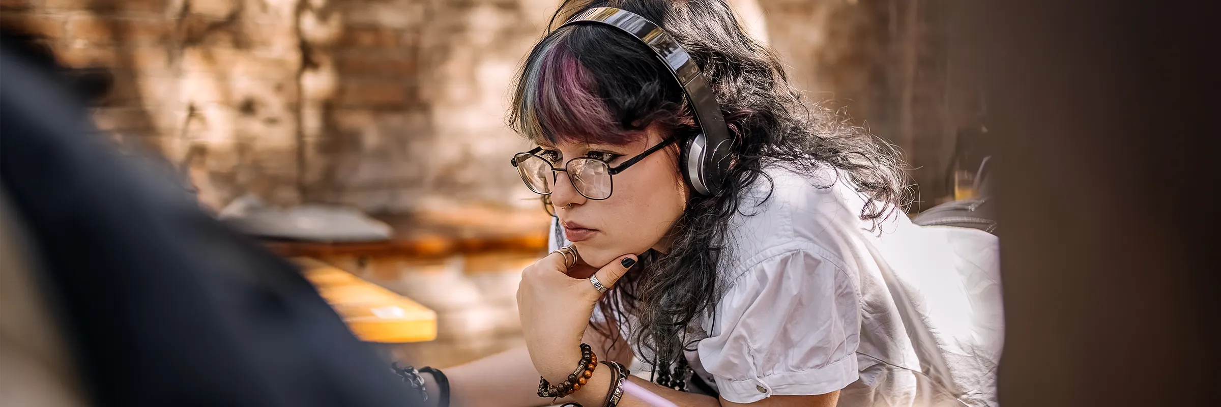 A person studies outside in the shade while wearing headphones.