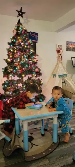 Medina's two children at a play table in front of their holiday tree