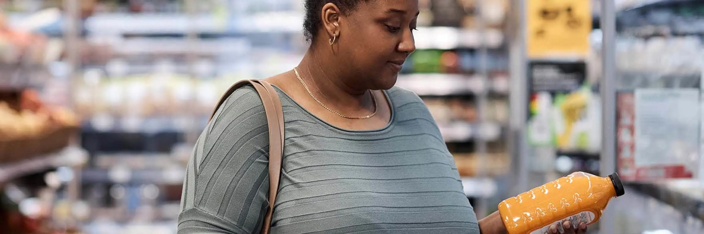 Woman shopping for groceries and looking at a bottle of orange juice