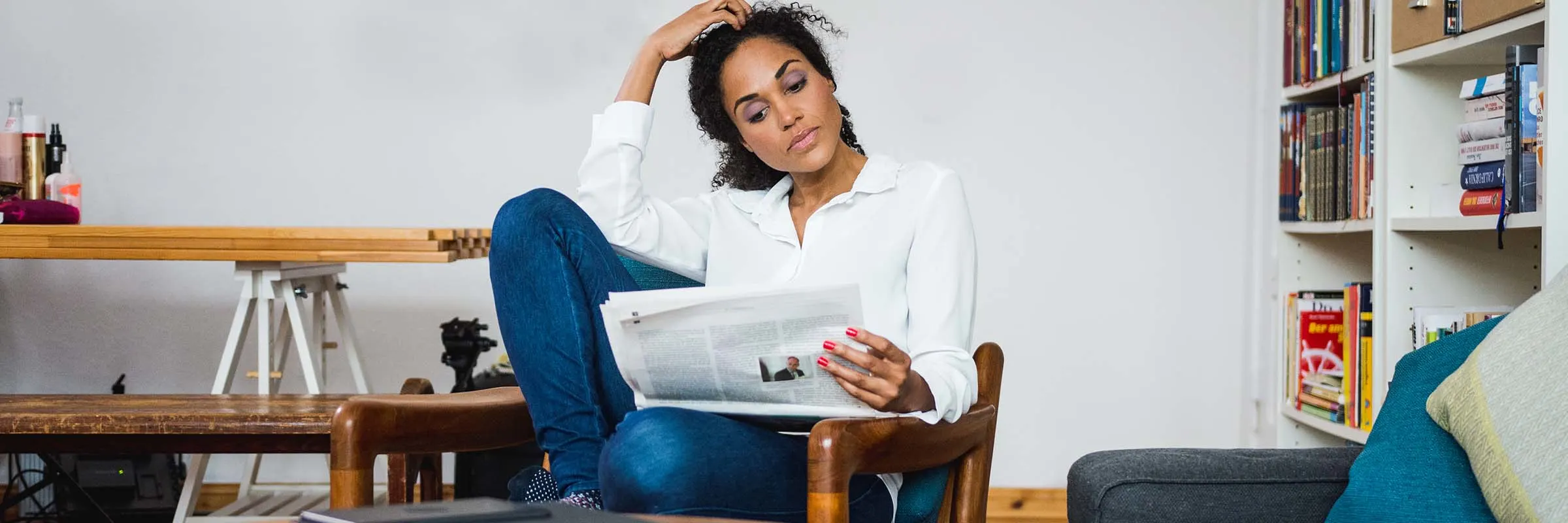 Woman sits in an armchair and reads a newspaper