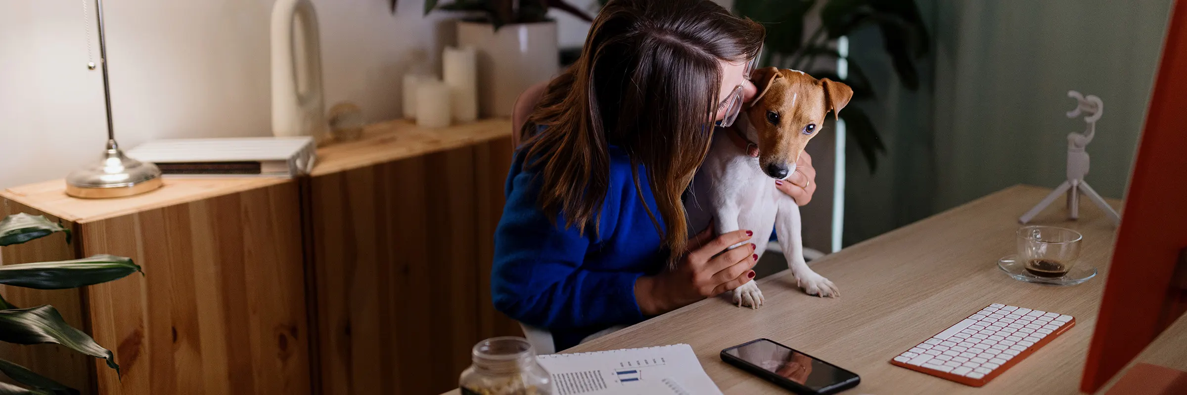 A woman works on her taxes at home while holding her dog.