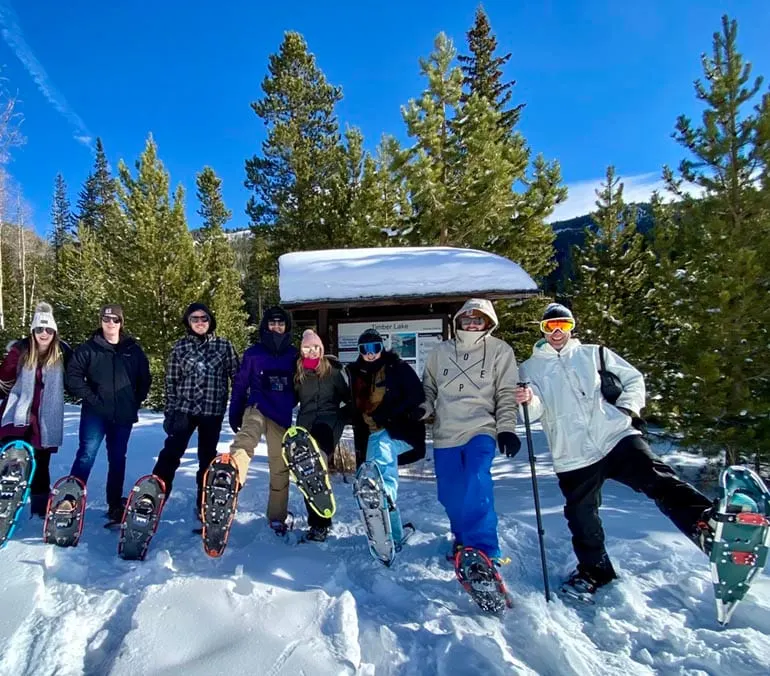 Alex Bowman and his friends pose with snowshoes on while standing in a snow-covered area