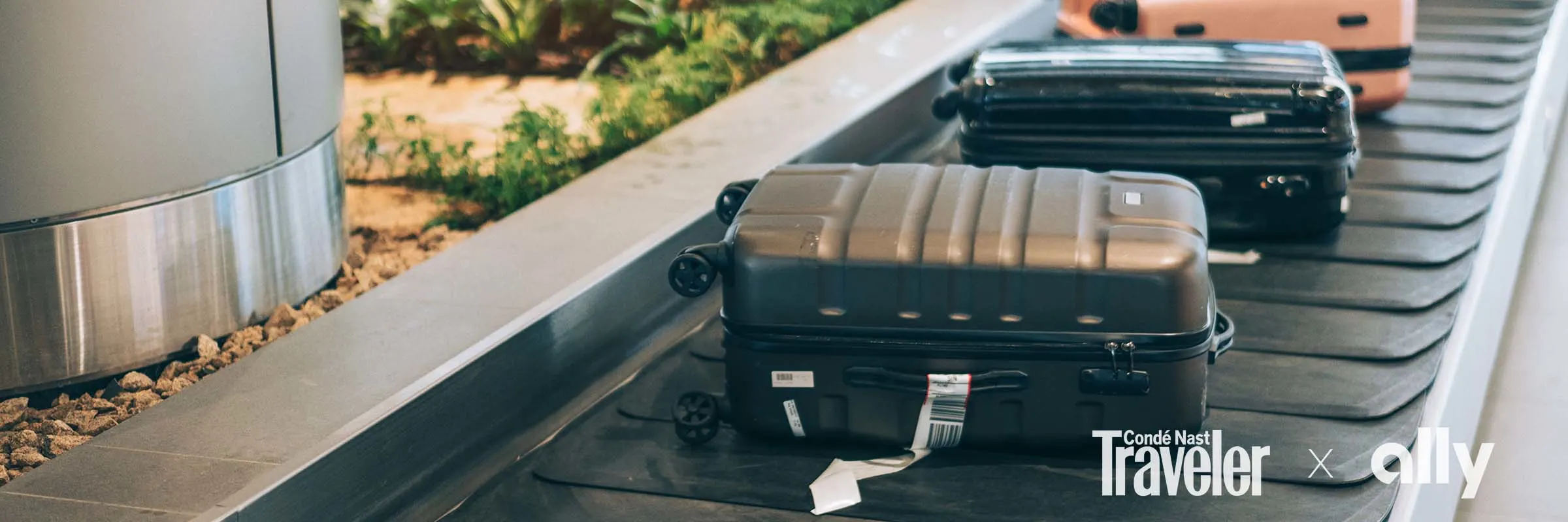 Suitcases line a conveyor belt at an airport.