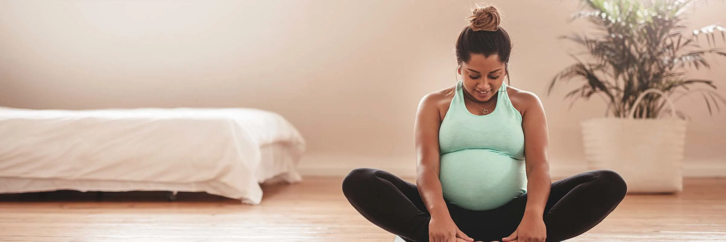 A pregnant black woman stretches into a yoga pose