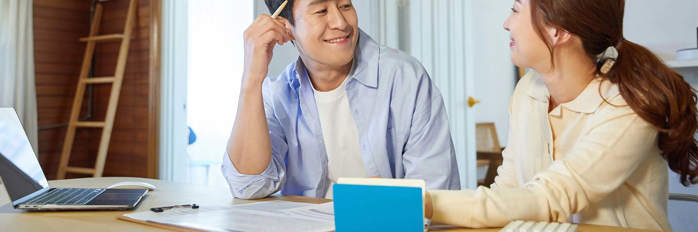 Young couple sitting at a table with their laptop, bills and calculator discussing finances