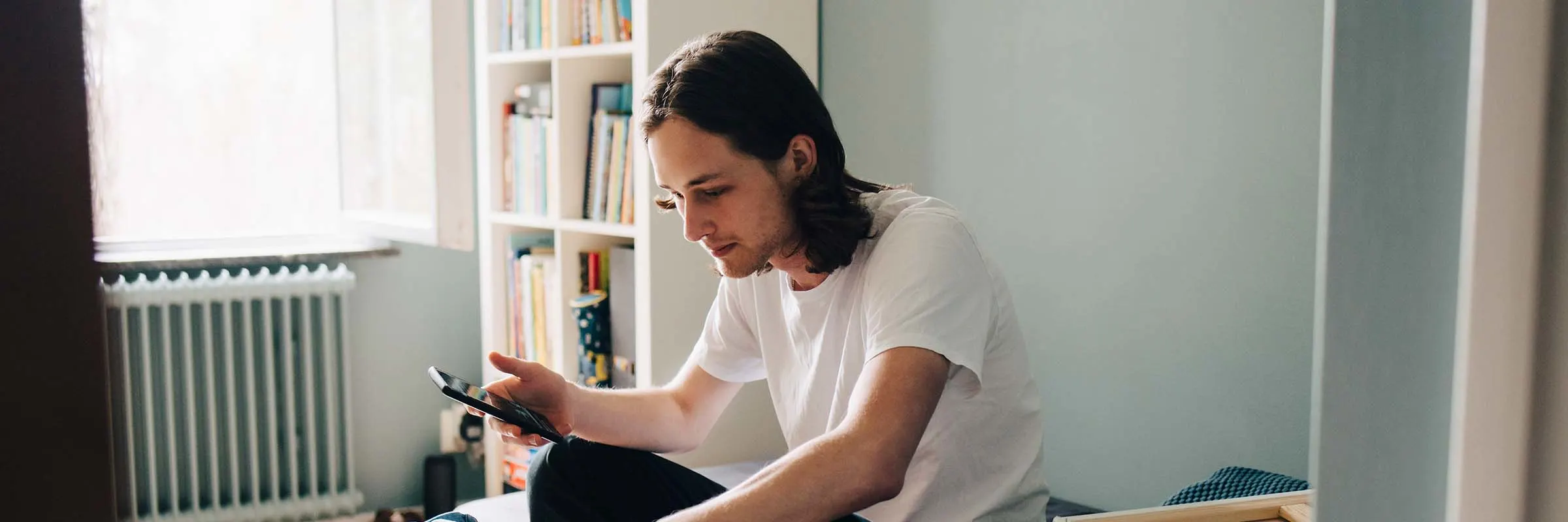 Man pauses while packing a box to look at a message on his mobile phone