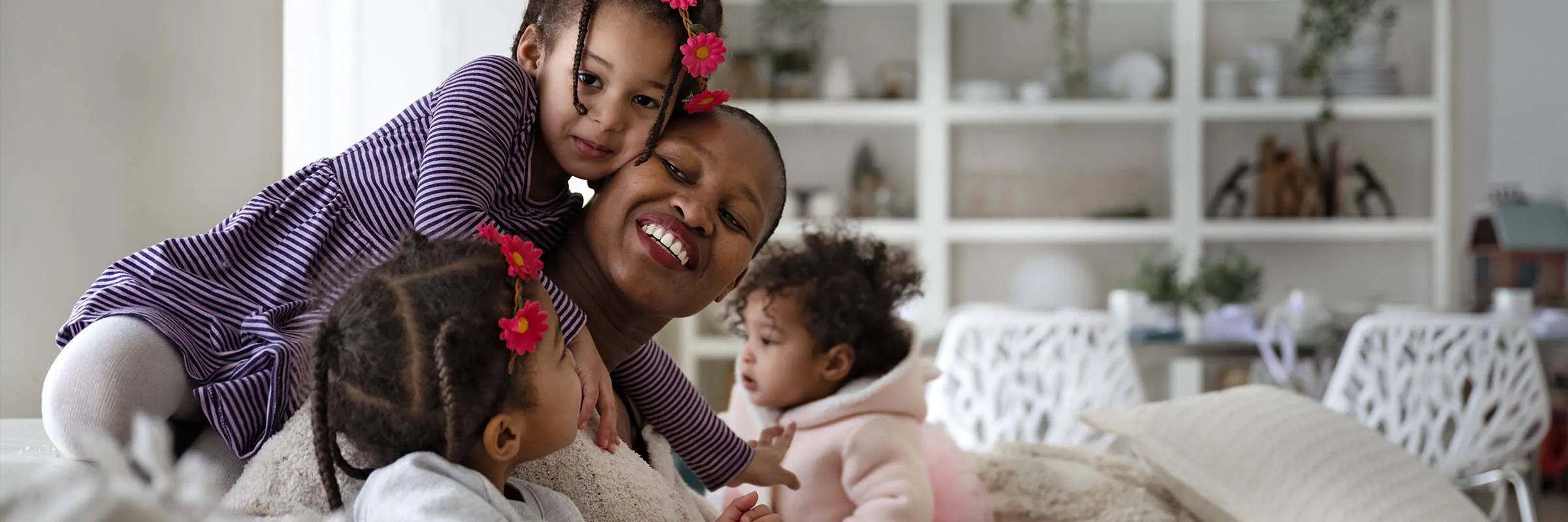 Image of a woman and her three daughters playing on the sofa