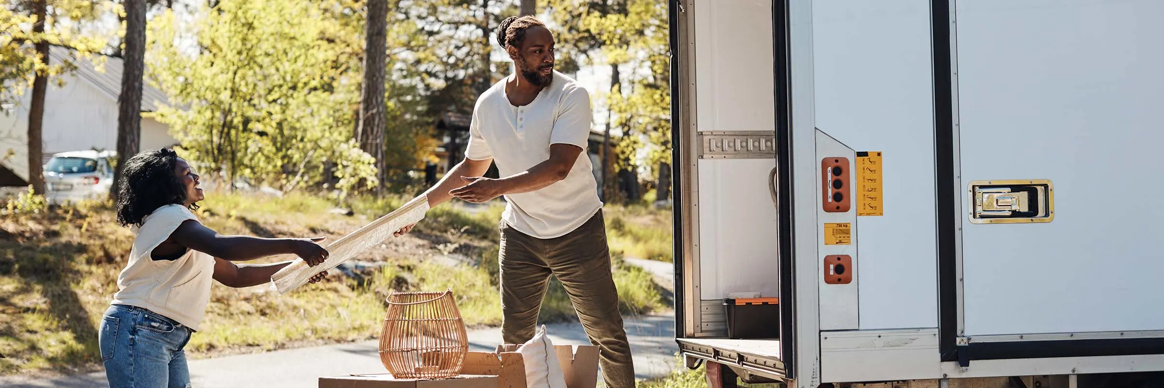  A man is passing a picture frame to a woman from a moving truck.