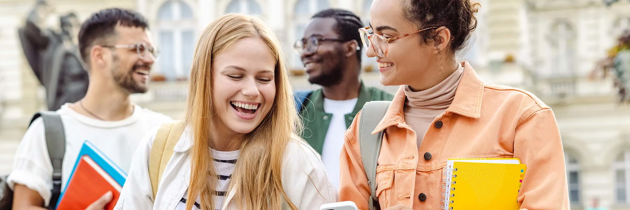 Image of two friends laughing at something on a phone while walking to class