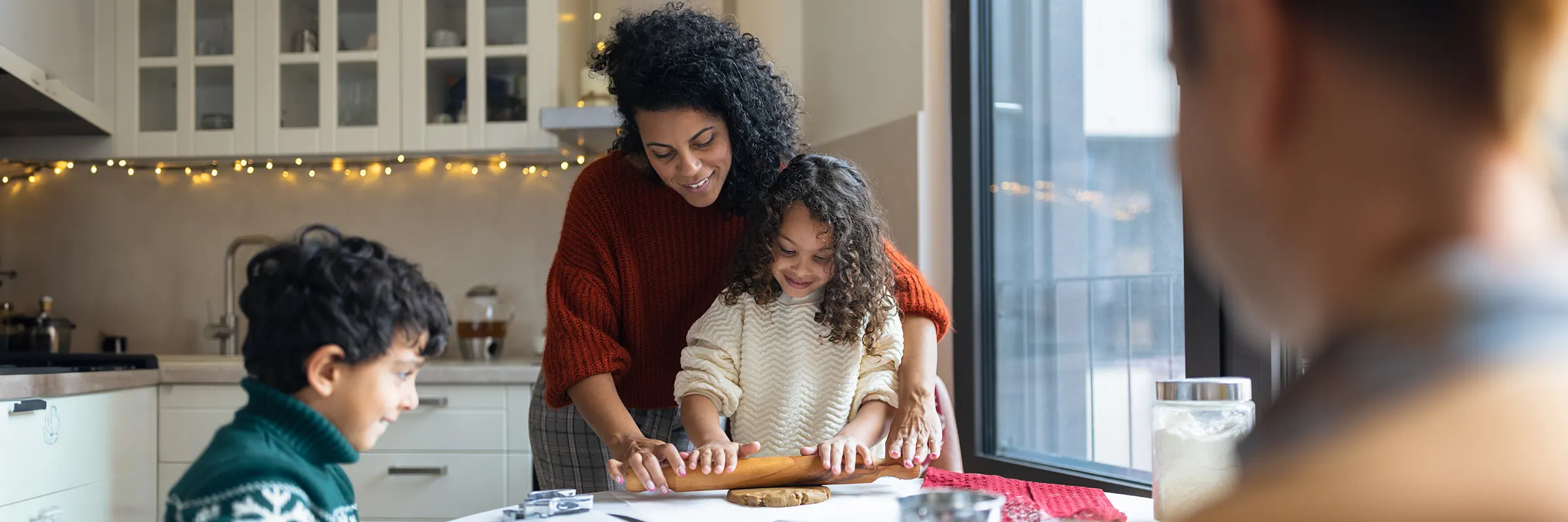 A woman and her two kids bake holiday cookies.

