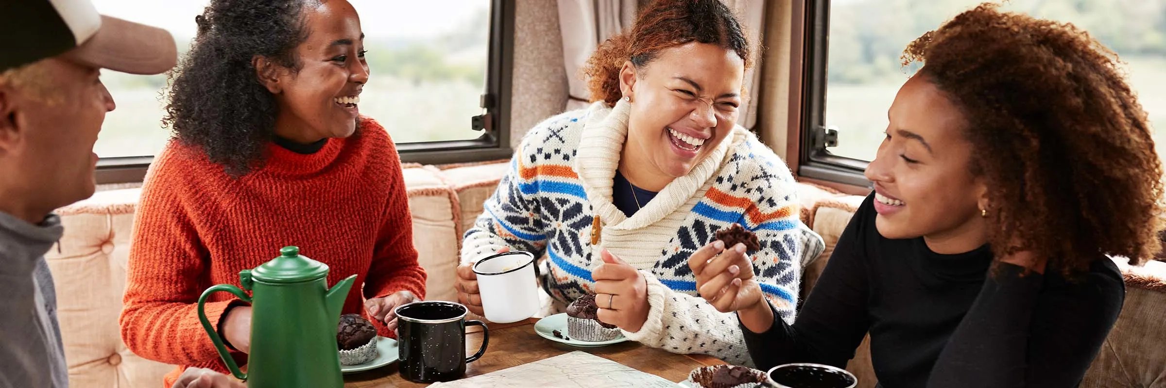 People sitting in an RV enjoying a cup of coffee while looking at a map. 