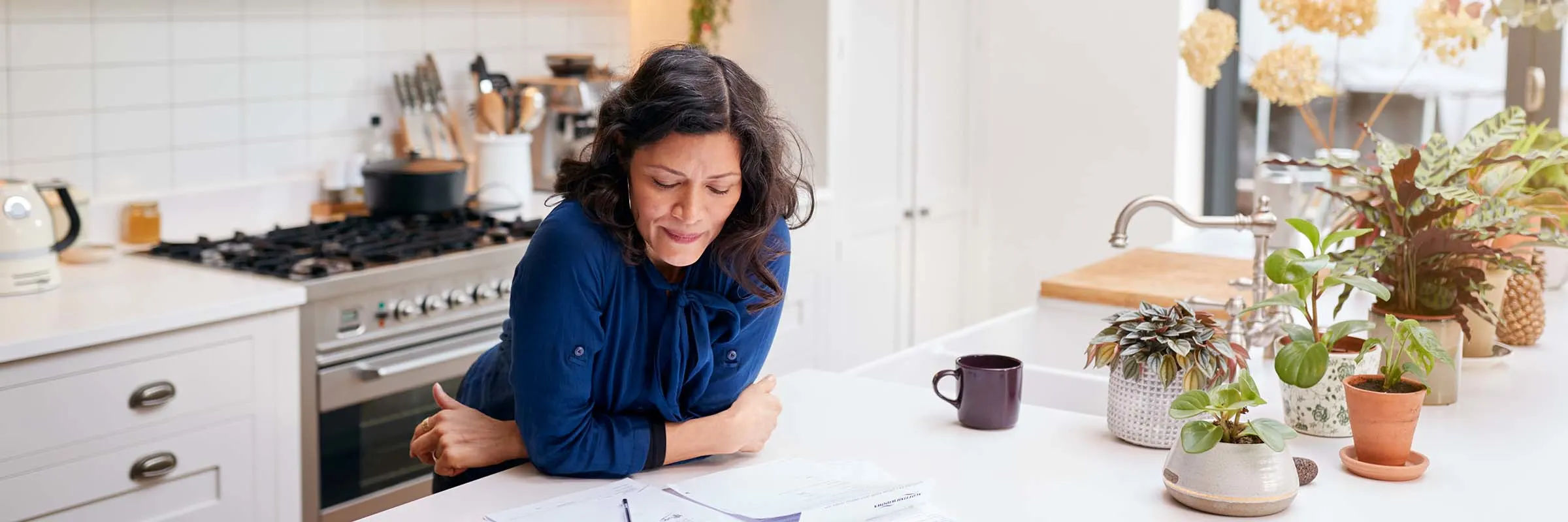  Woman looks over tax documents at the kitchen counter.