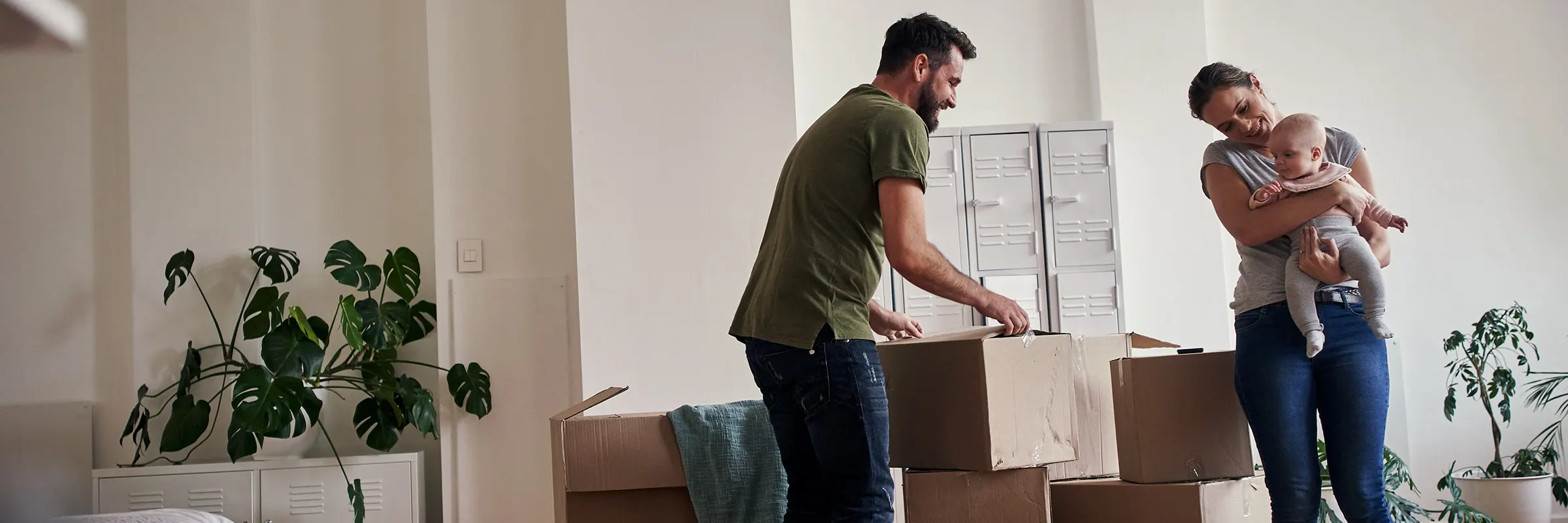 Couple with baby unpacks boxes in a new house