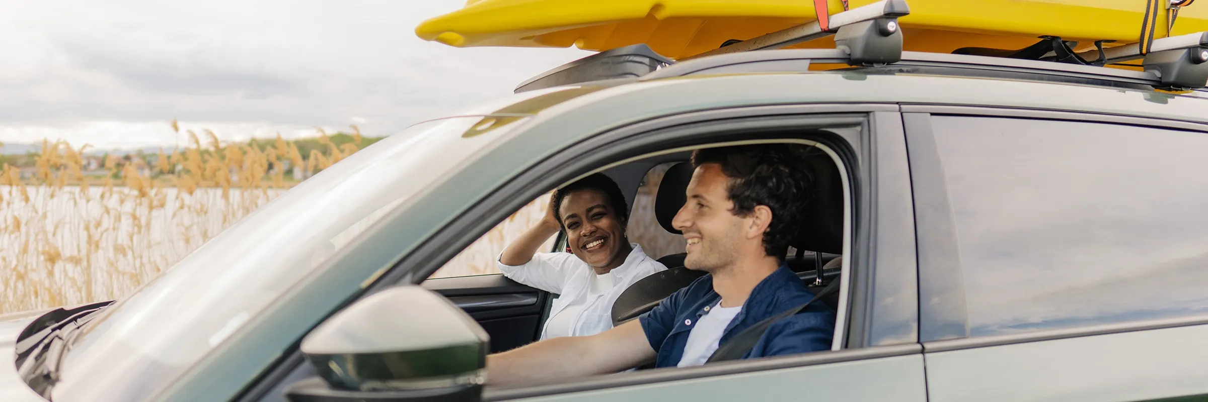 A couple smiling while driving to the lake.