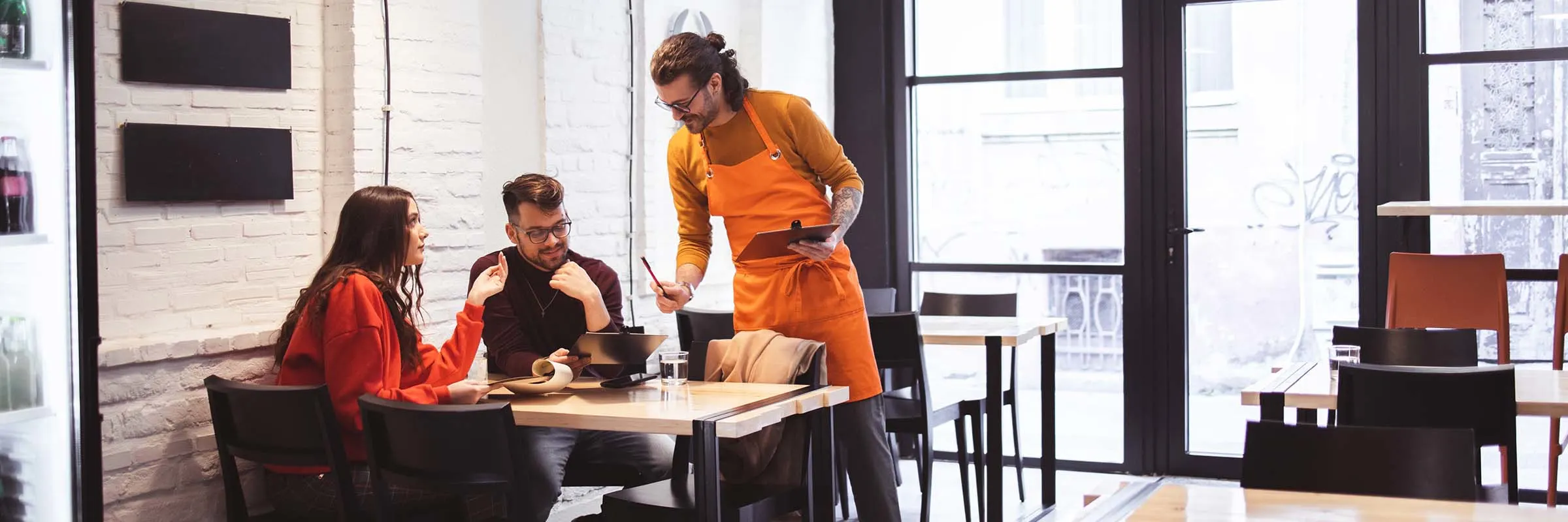 A waiter takes an order from a young couple at a restaurant