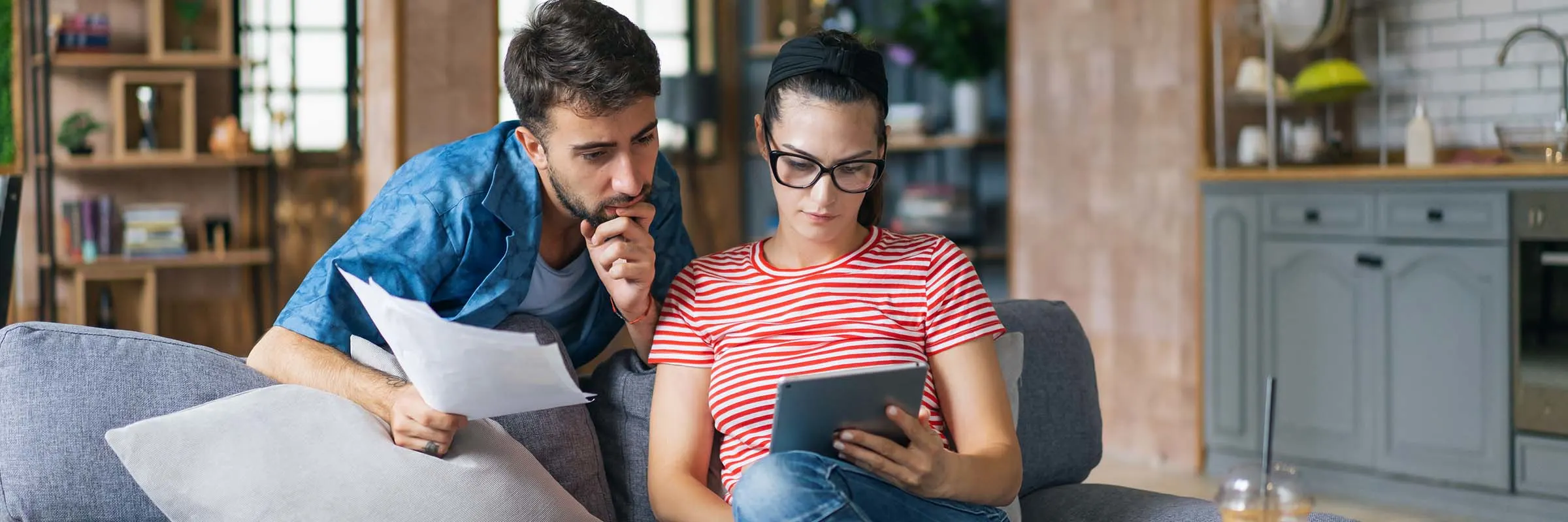 Couple at home on the couch calculating bills.