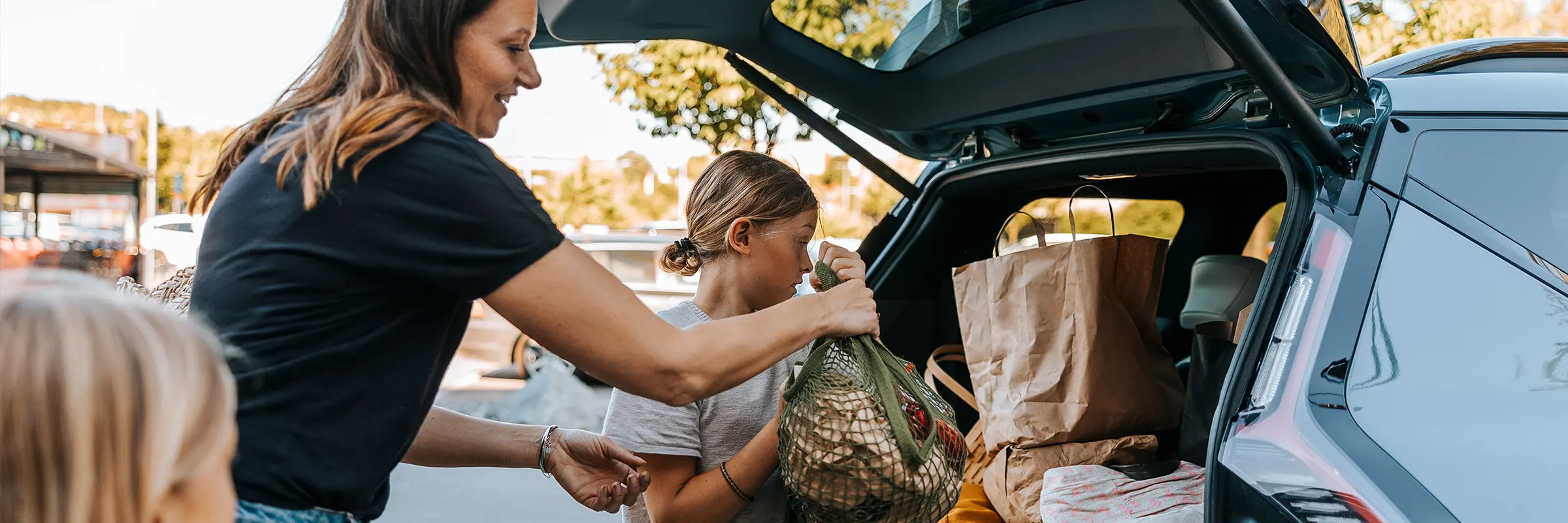 Woman packing the trunk of the car with her kids. 