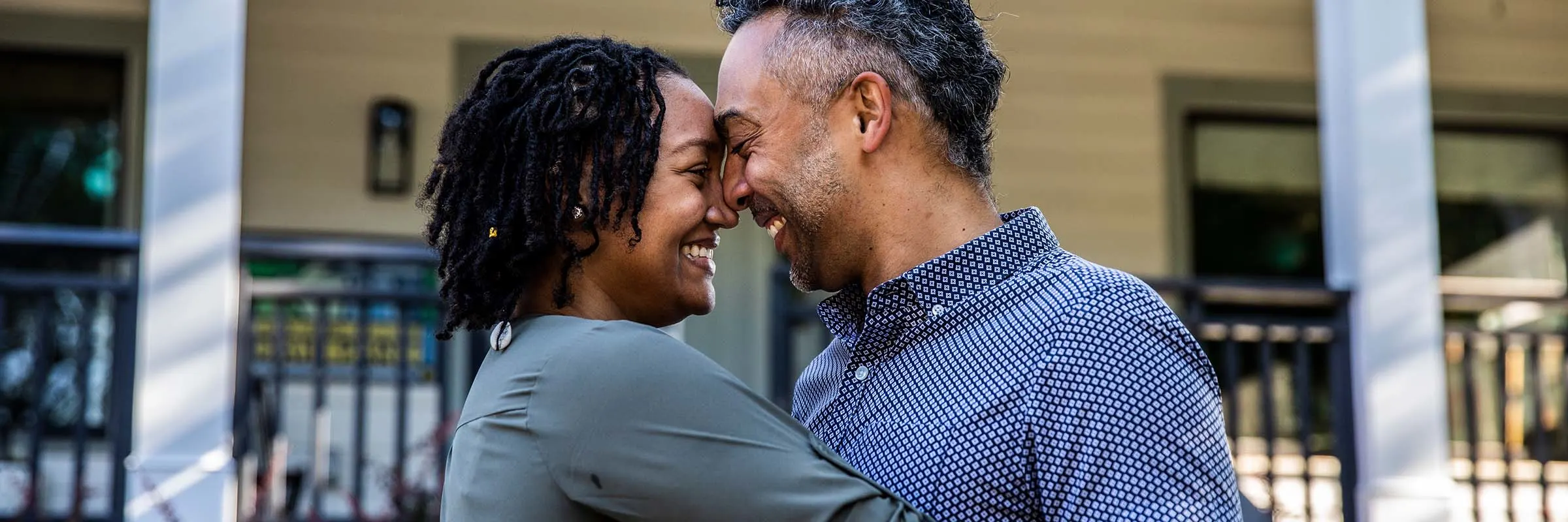 Husband and wife embracing in front of home. 