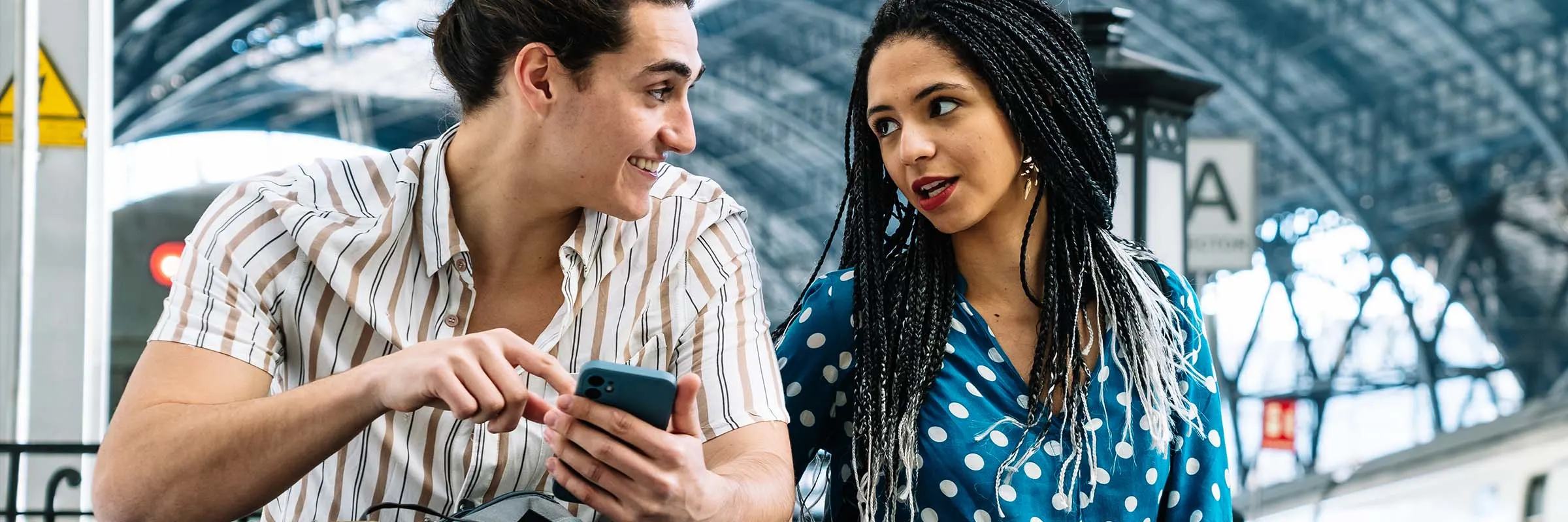 Young couple chatting about travel plans while waiting at a commuter train station 