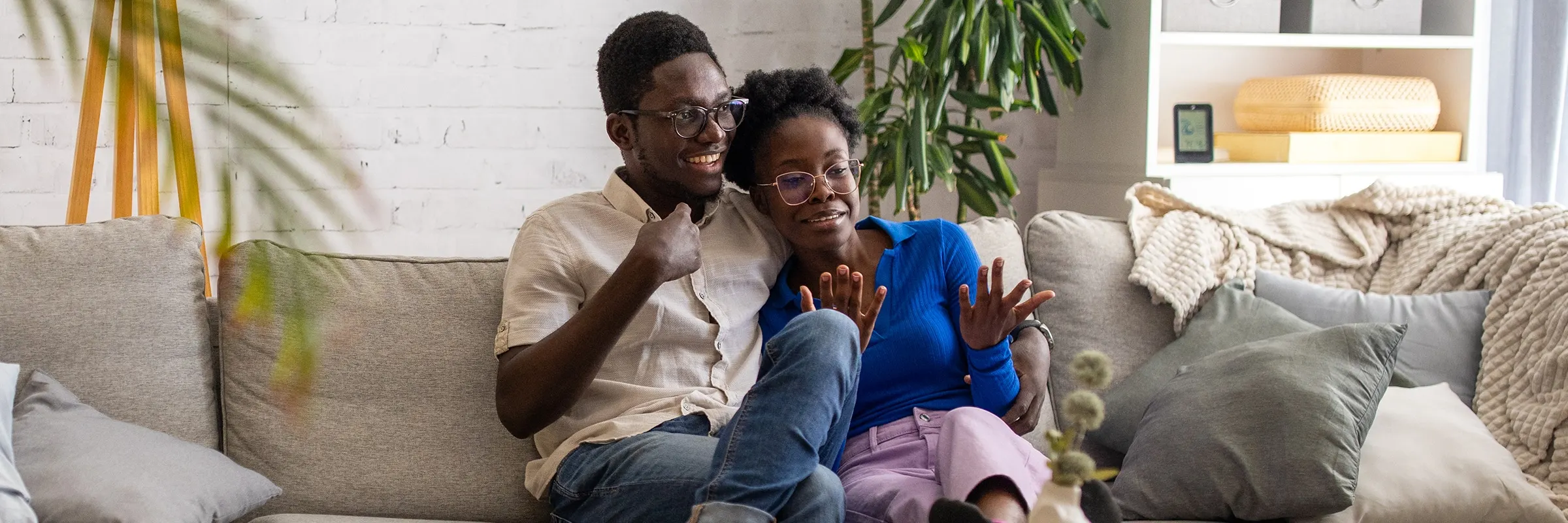 A couple sits together on a couch in their living room while having a conversation.