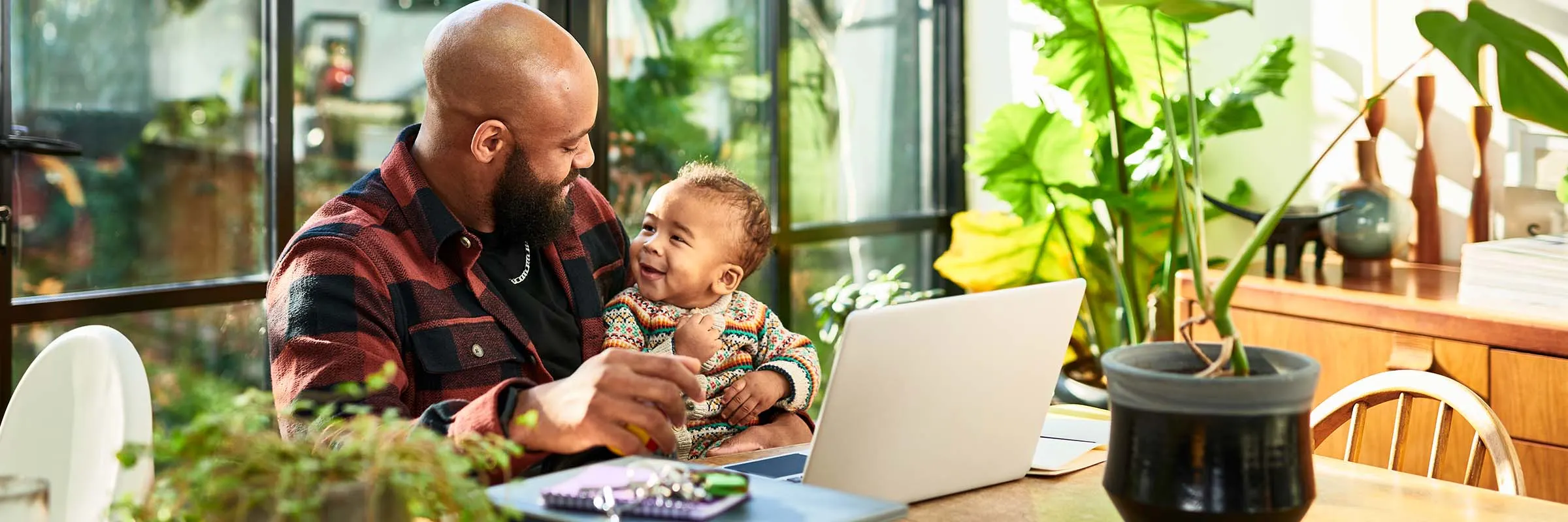 Father and young child sitting at kitchen table looking at the computer..