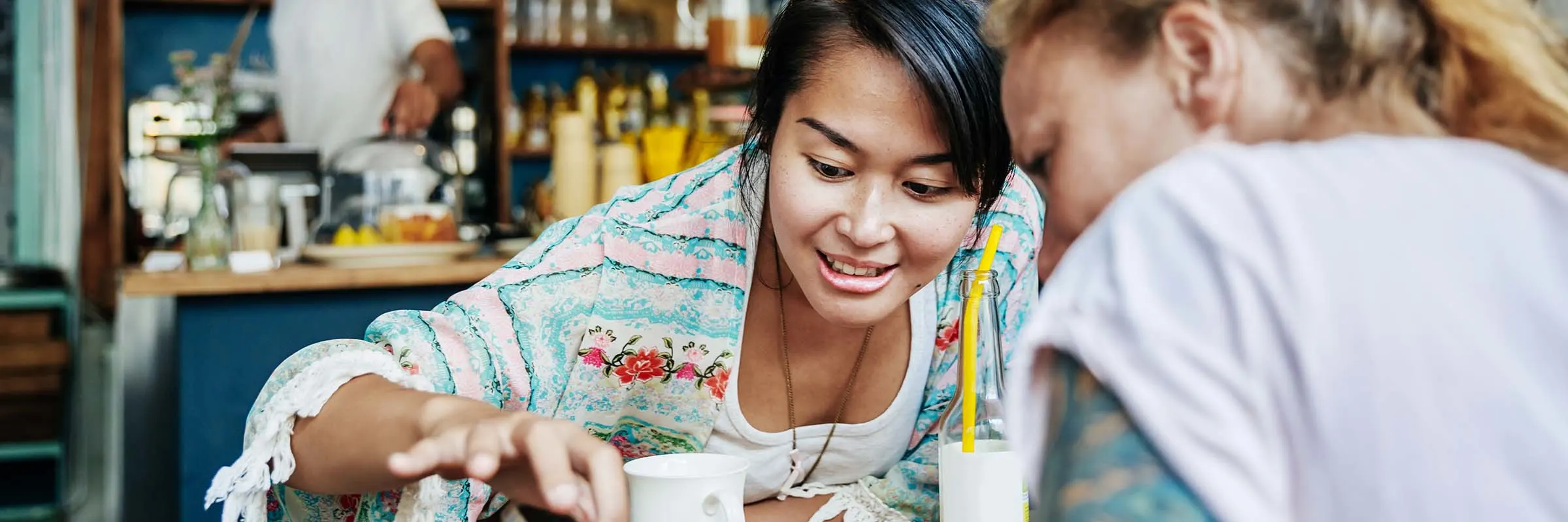 Two friends looking at a  smartphone in a  cafe