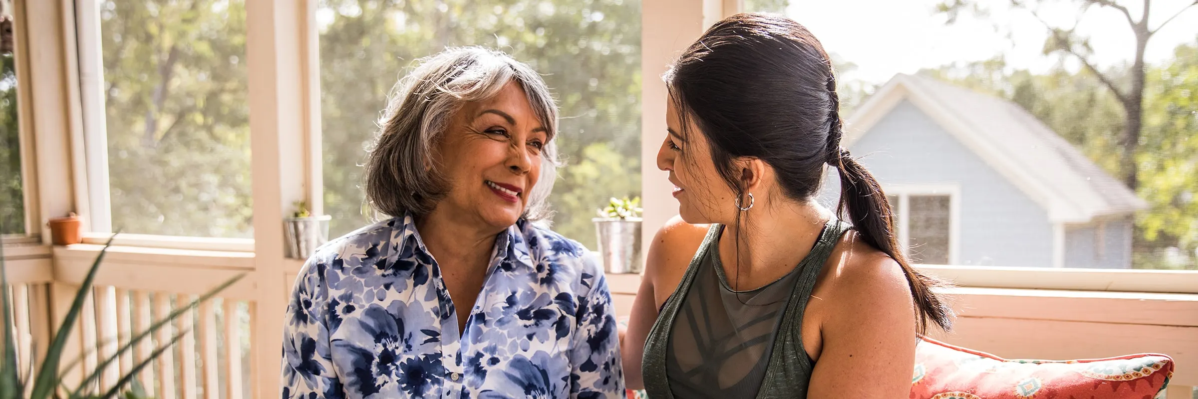 A mother and daughter sit happily together on the porch