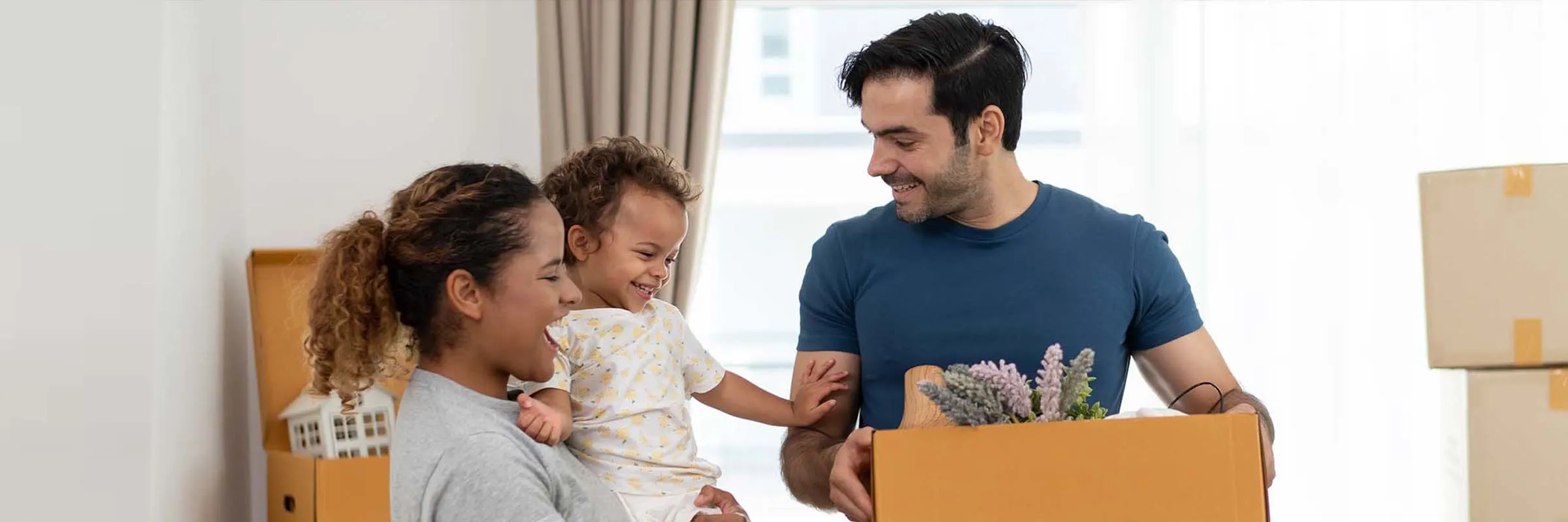 A happy family of three smiles as they move into their new place.