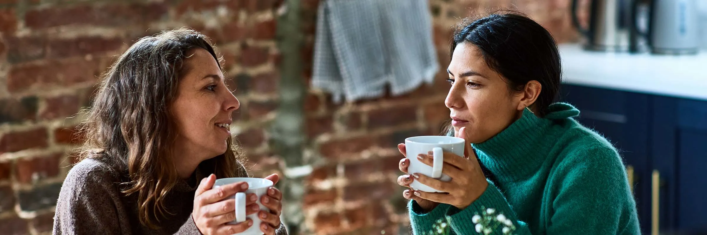  Two friends drink tea and talk at a kitchen table