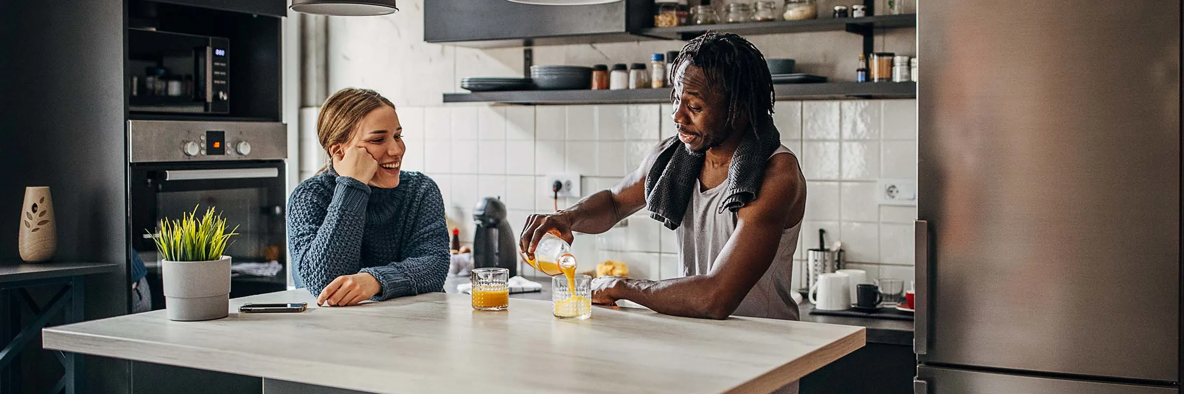 Image of a couple drinking orange juice at their kitchen counter