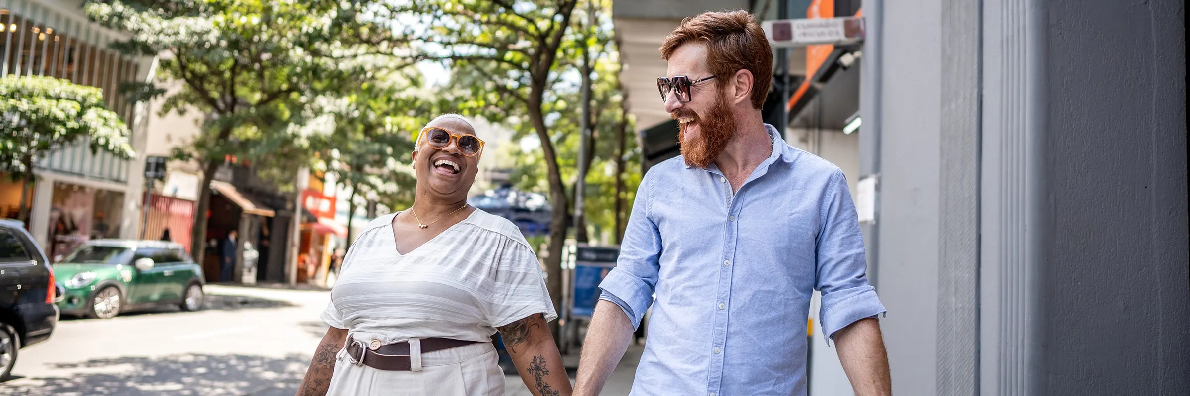 Couple holds hands while walking along a city street