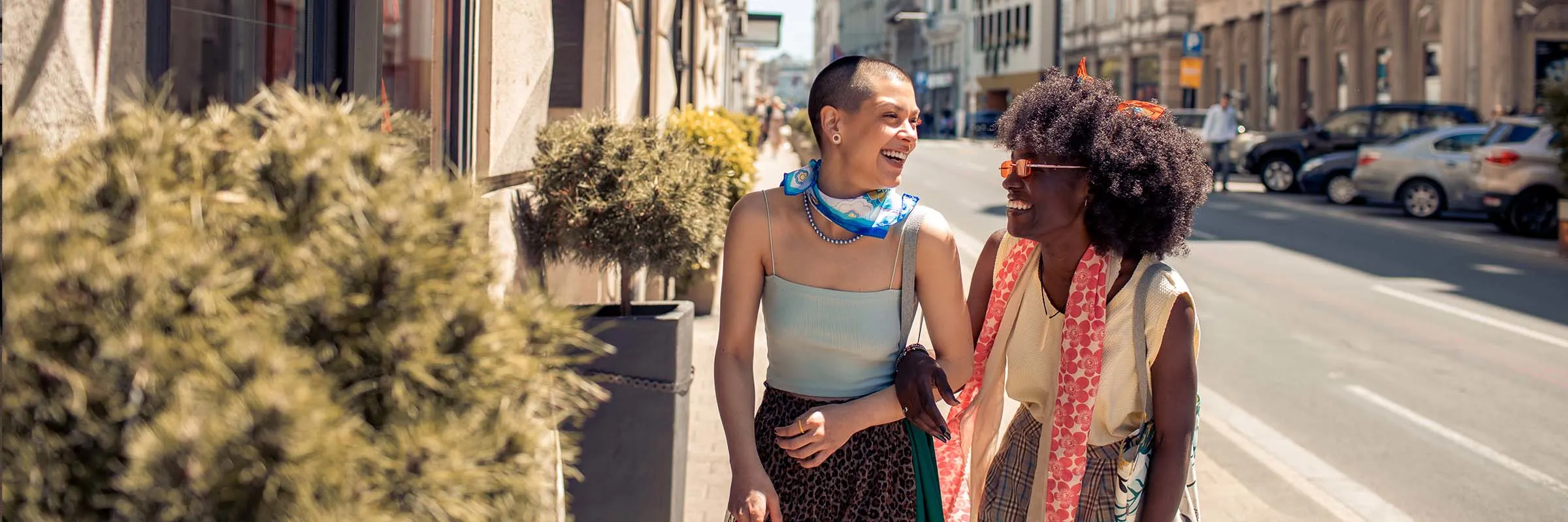  A female couple smiling and laughing as they walk through the city