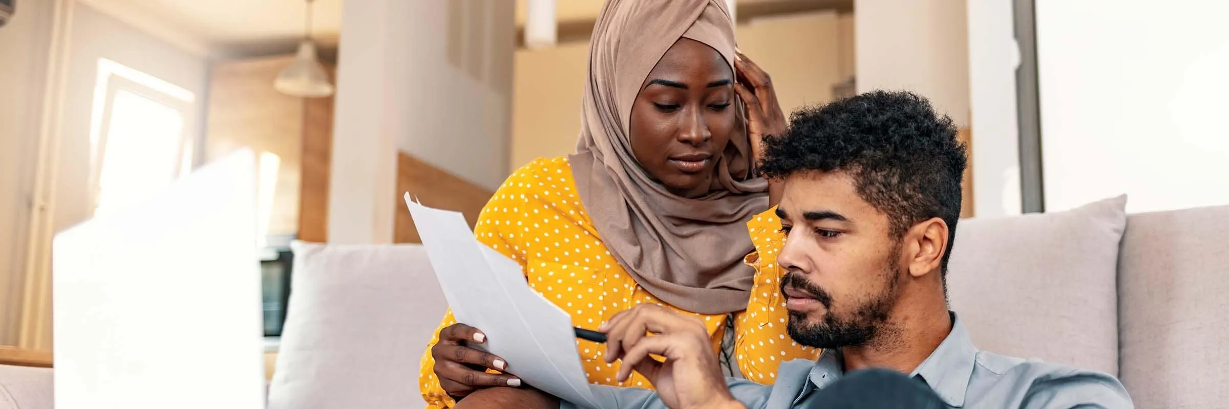 couple looking at paperwork together while sitting in their living room.