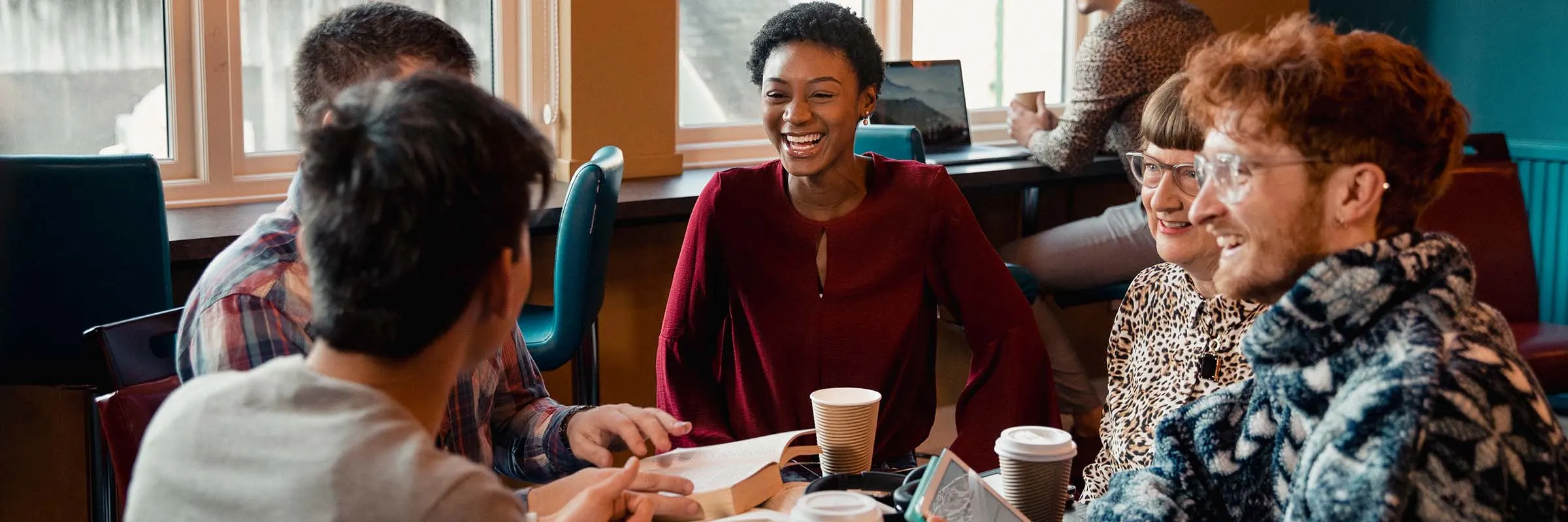 A group laughs over coffee at a cafe