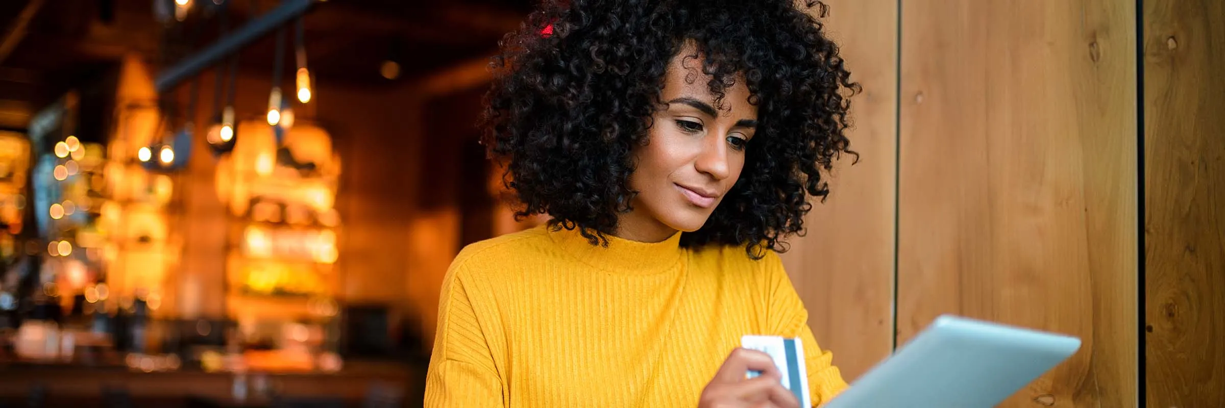 Beautiful smiling African American woman using digital tablet at the bar.