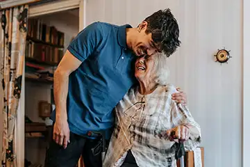 Elderly woman being embraced by her grandson.