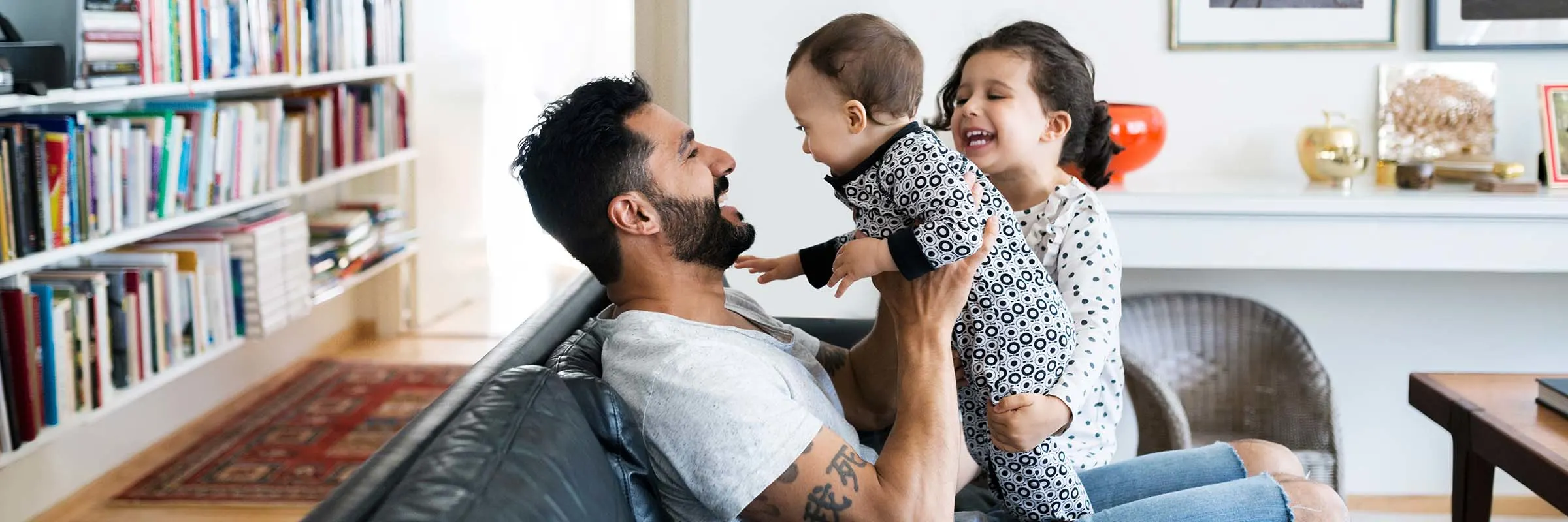 Father sitting on couch playing with two kids