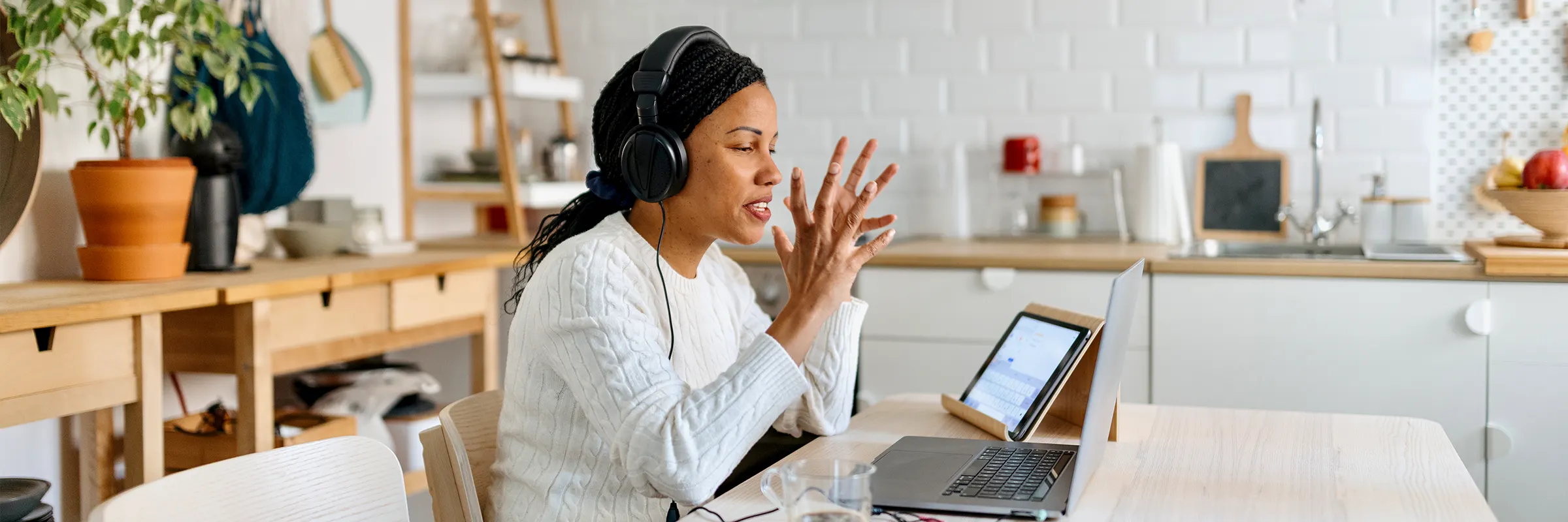 A woman on a video call talks at her kitchen table.