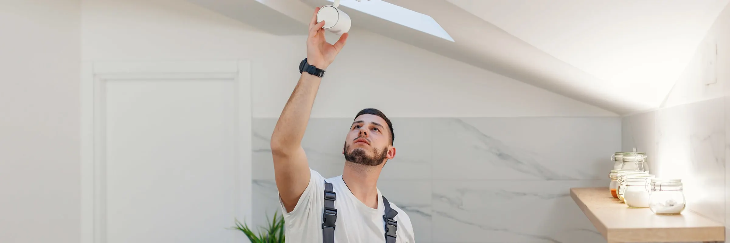  A man inspects a lighting fixture in the kitchen of a home.